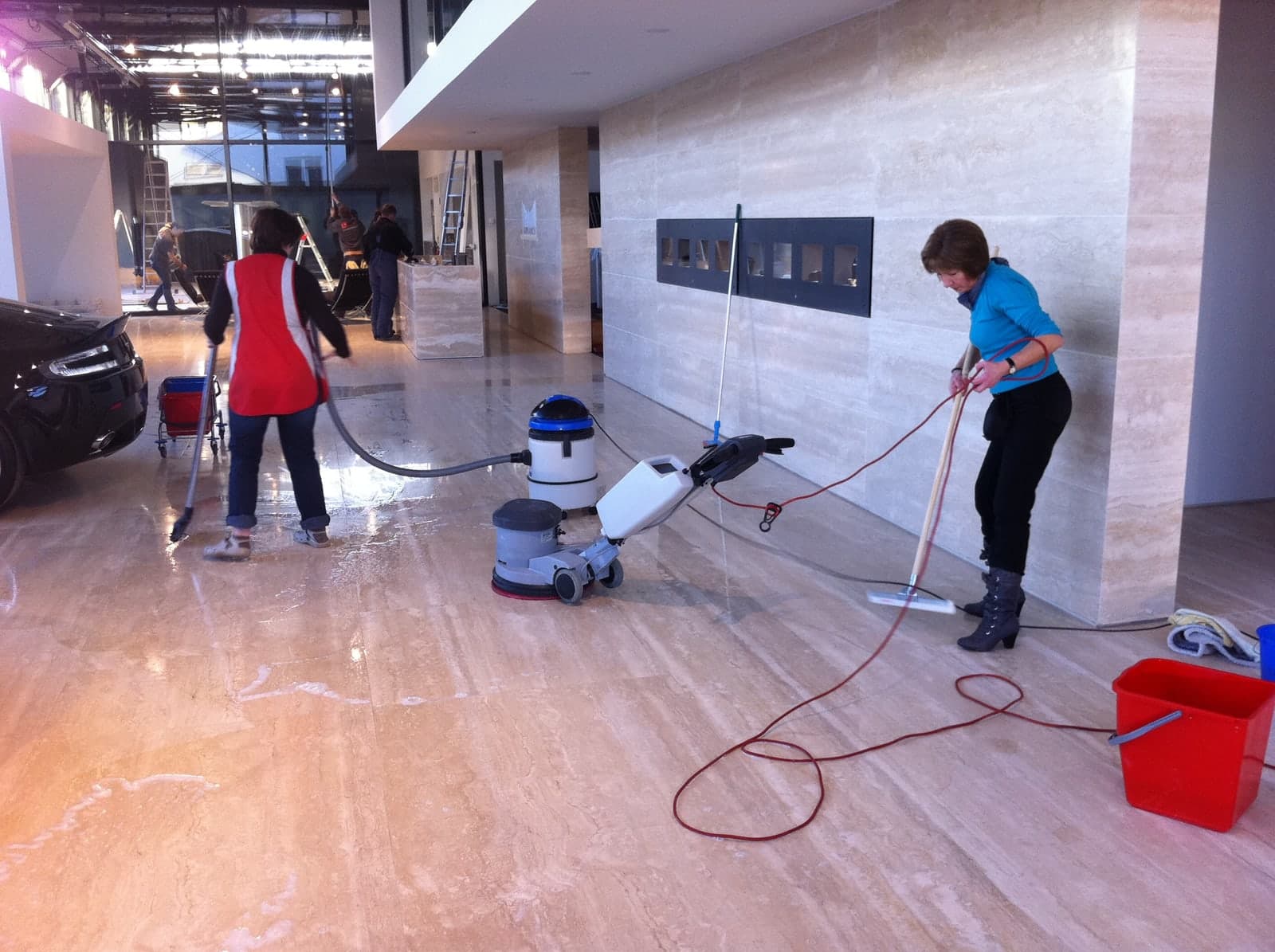 Agentes d'entretien lavant le sol en marbre d'un hall après travaux, avec monobrosse et aspirateur à eau